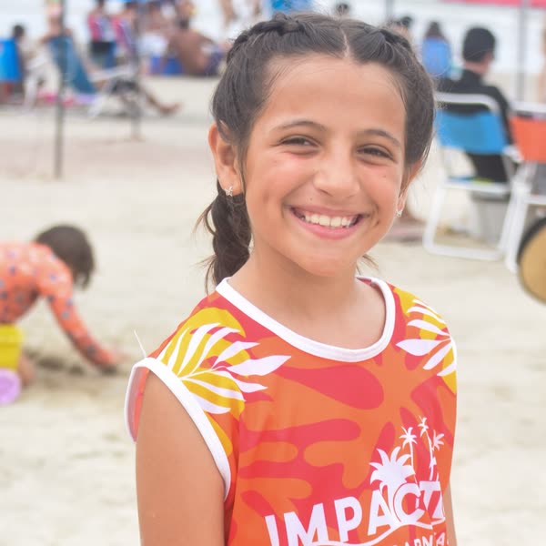 Menina sorrindo com a camiseta laranja do Impacto