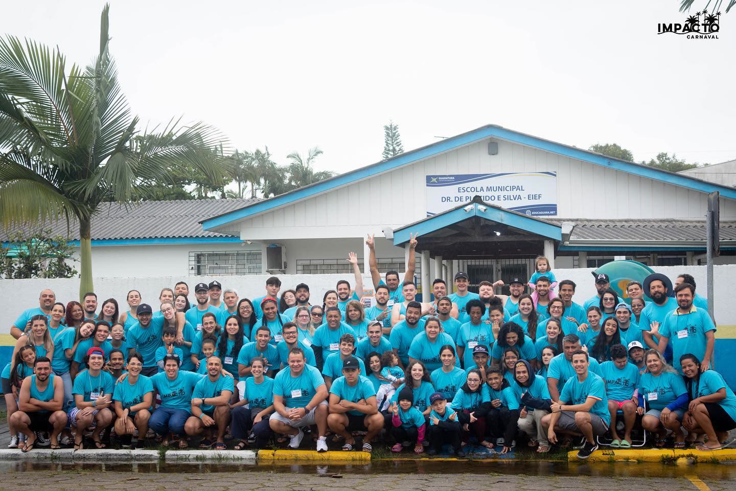 Equipe do Impacto de 2023, de camiseta azul, em frente à escola